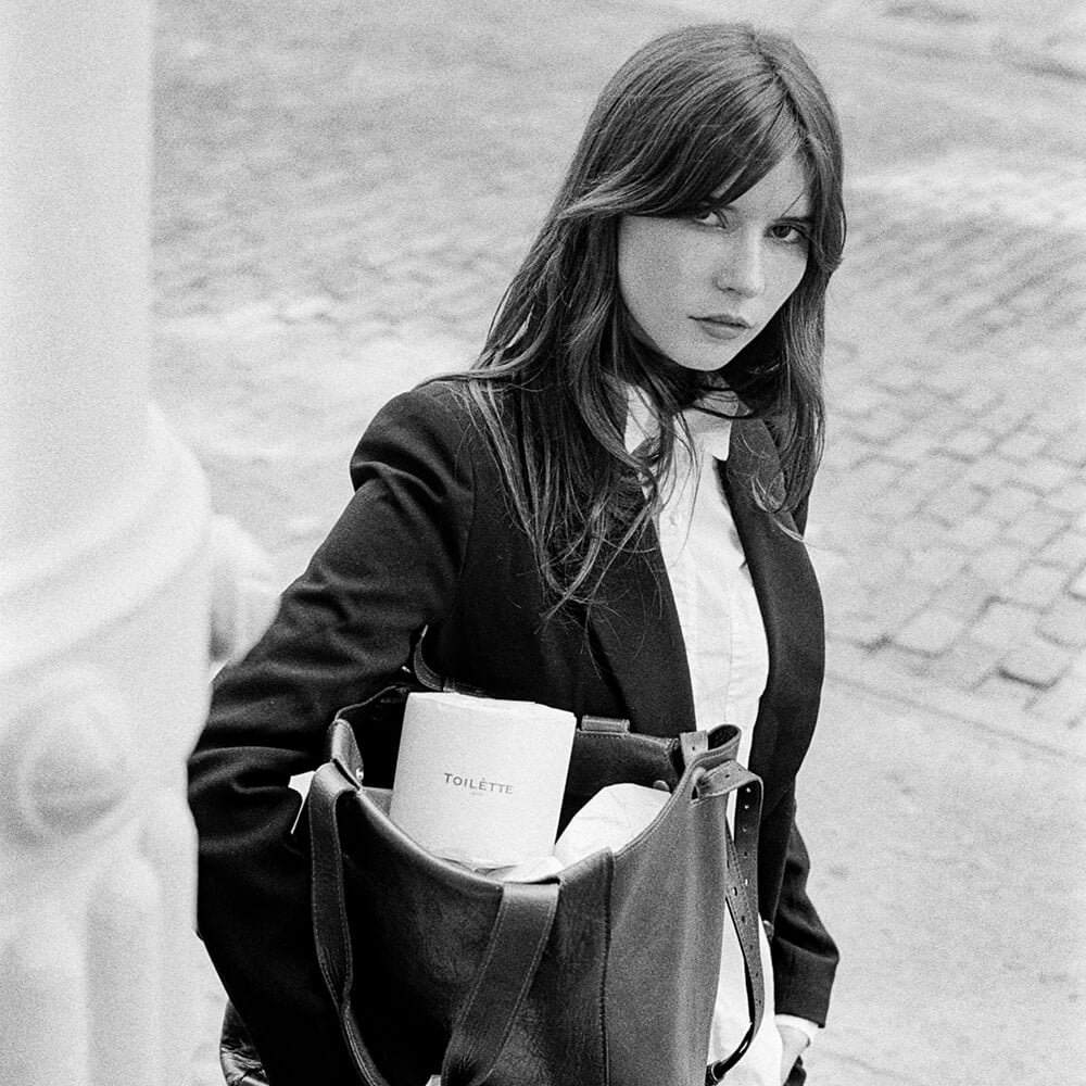 girl on stoop in nyc with rolls in leather bag