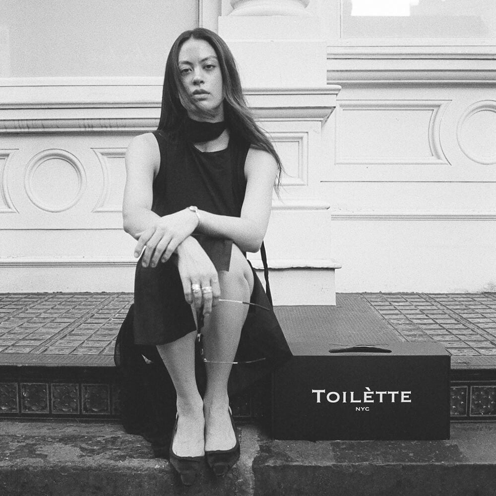 women on sidewalk seated next to box of Toilètte 