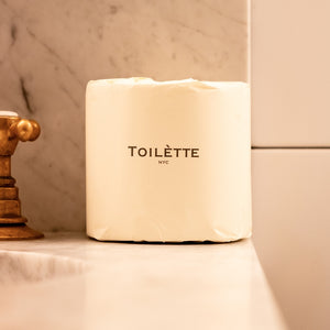 TOILETTE TP roll in 'Light' color on a bathroom shelf with marble wall background