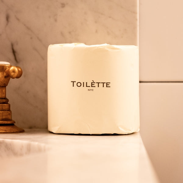 TOILETTE TP roll in 'Light' color on a bathroom shelf with marble wall background